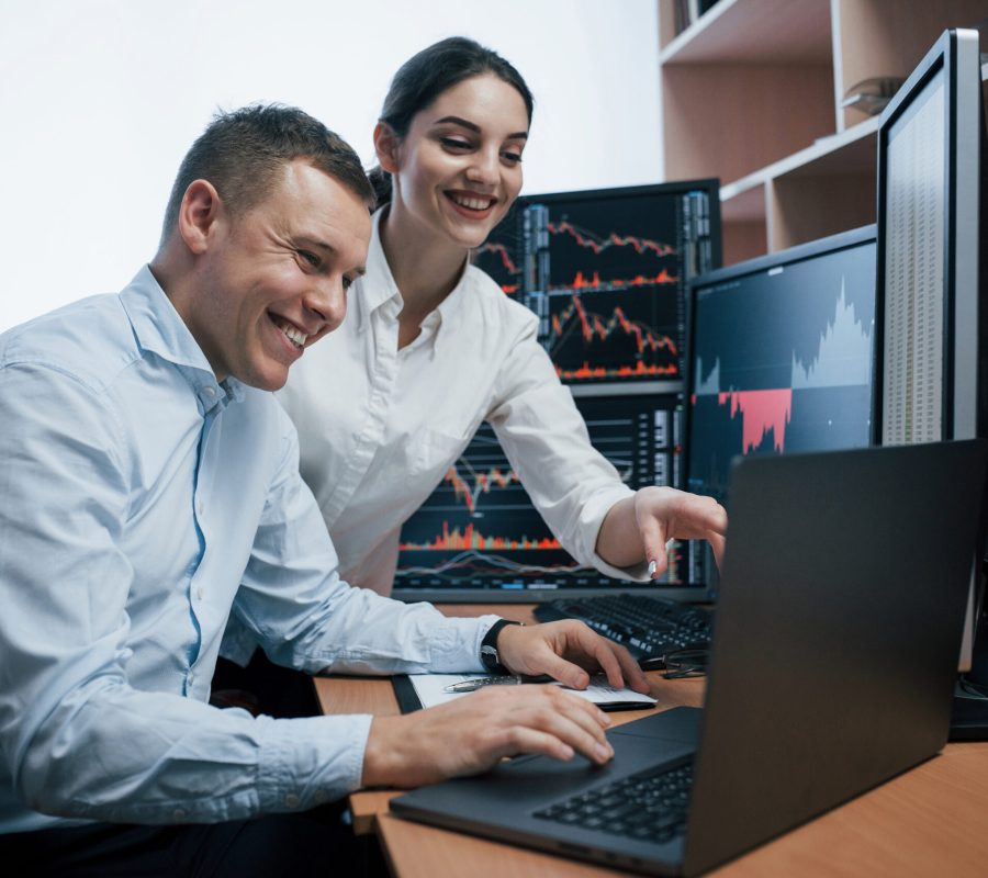 Team of stockbrokers are having a conversation in a office with multiple display screens.